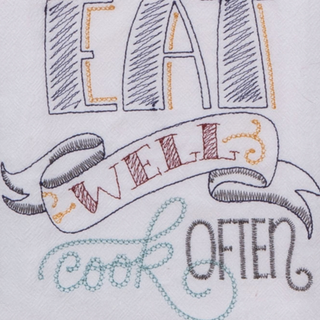 Close-up of embroidered text on a white fabric background, reading “EAT WELL cook OFTEN” in gray, orange, red, and blue thread.