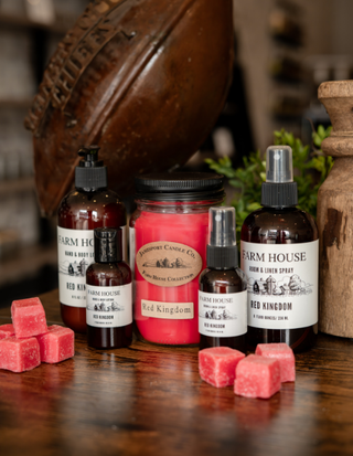 Collection of Farm House Red Kingdom products including bottles, candles, and soap on a wooden surface.