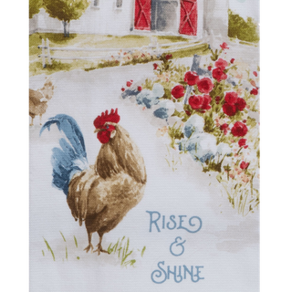 A rooster printed on a towel with flowers and a barn in the background, featuring the text 'Rise & Shine'.