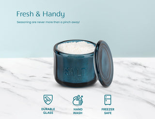 Blue glass container with salt on a marble surface, featuring text and icons about durability, hand washability, and freezer safety.